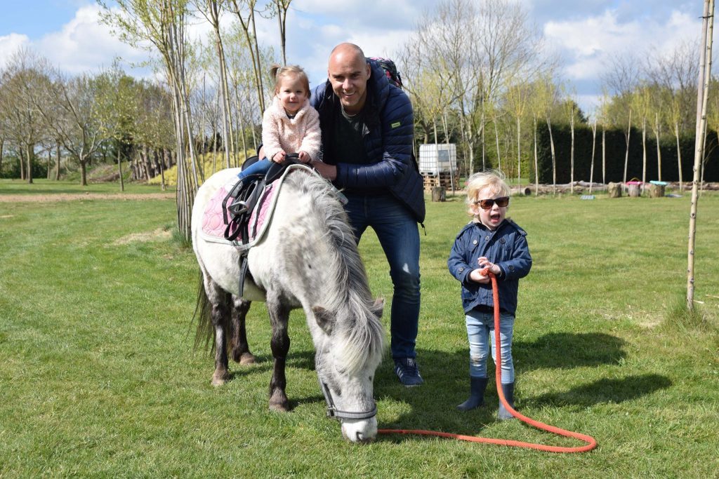 Kinderen rijden met papa op de pony